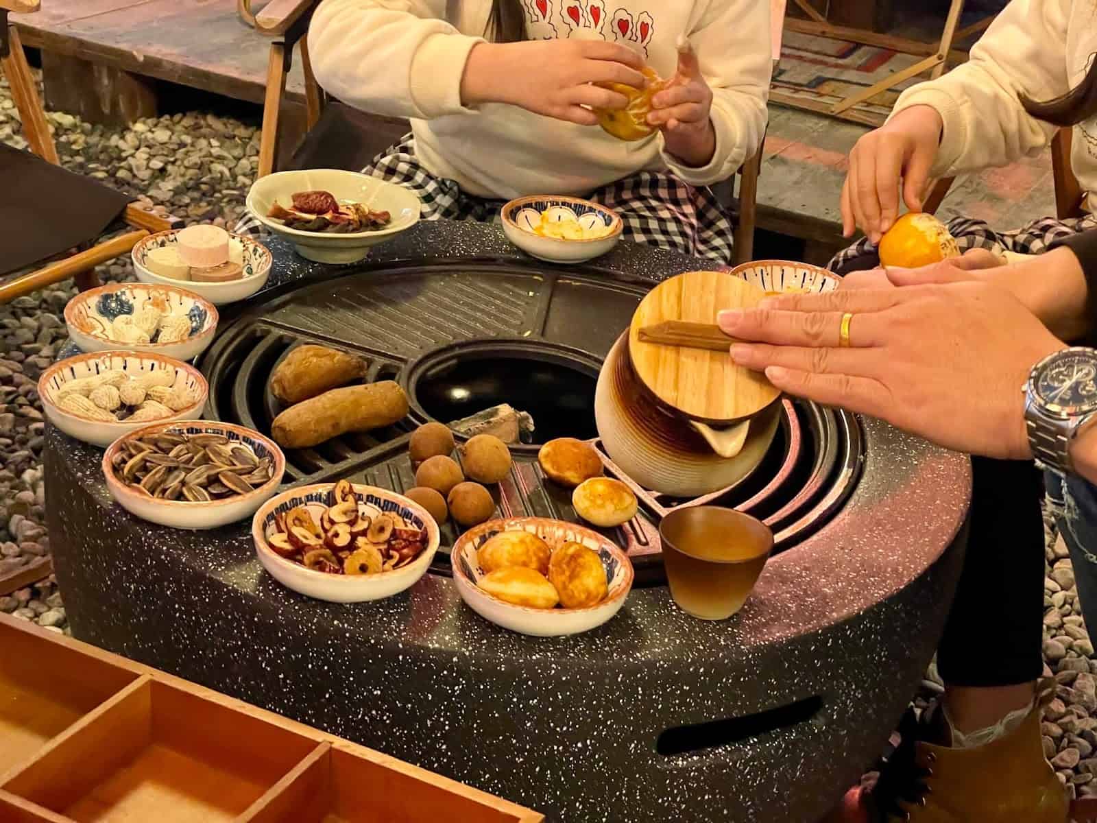 圍爐煮茶，將陶壺中煮好的茶倒到陶杯中